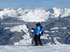 A couple consulting a piste map with the mountains above Stumm on the other side of the Zillertal in the background.